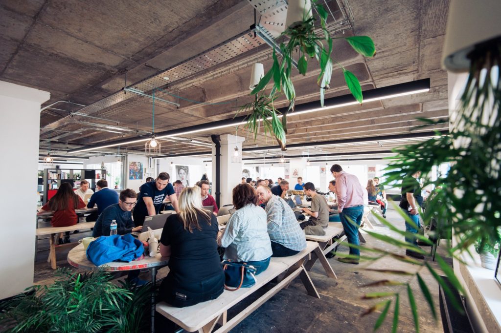 Photograph of the coworking space at Launch 22 - rows of desks and benches with people sat working at them.